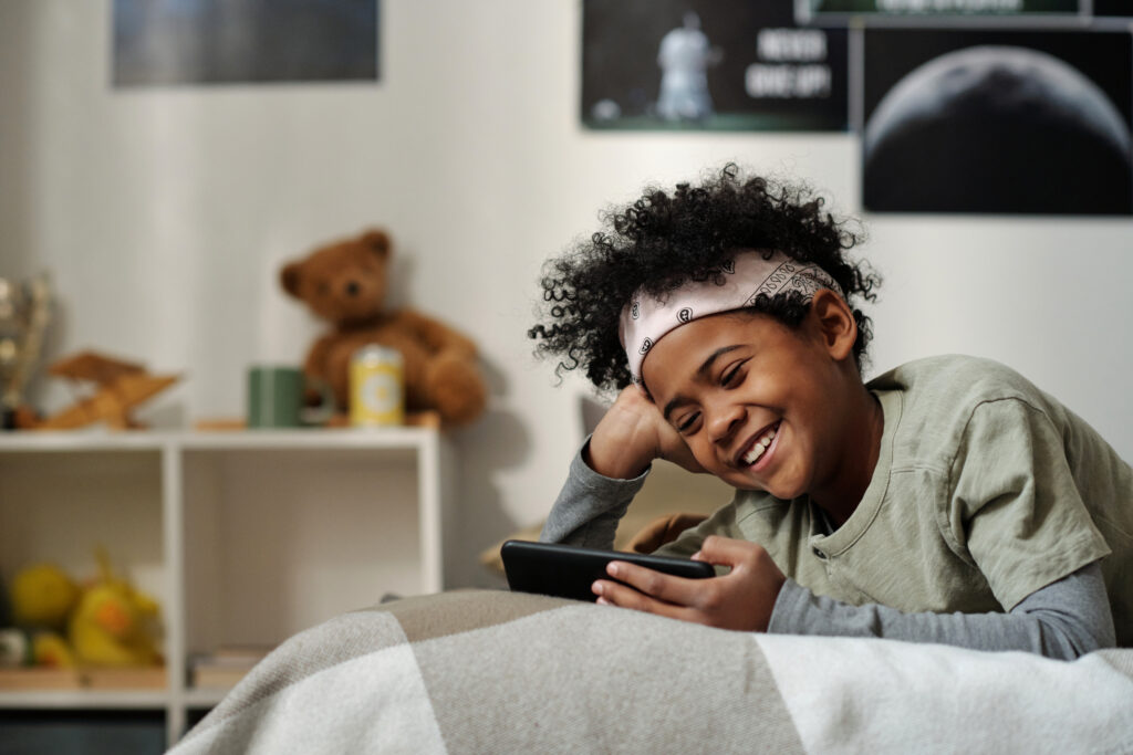 Effects of screen time on child development: finding the balance 1 child on bed smiling at phone screen