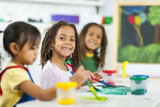 Diverse group of elementary students painting and doing art together.